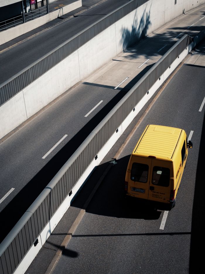 journey-img Aerial view of a yellow van on an empty city highway, showcasing urban infrastructure and transportation.