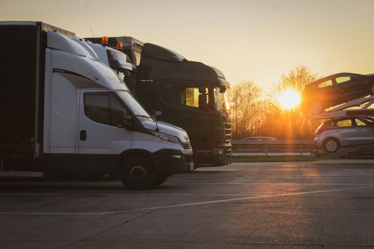 who-we-are-img A row of trucks and car transporter parked at sunset in an open parking lot, highlighting the golden hour.