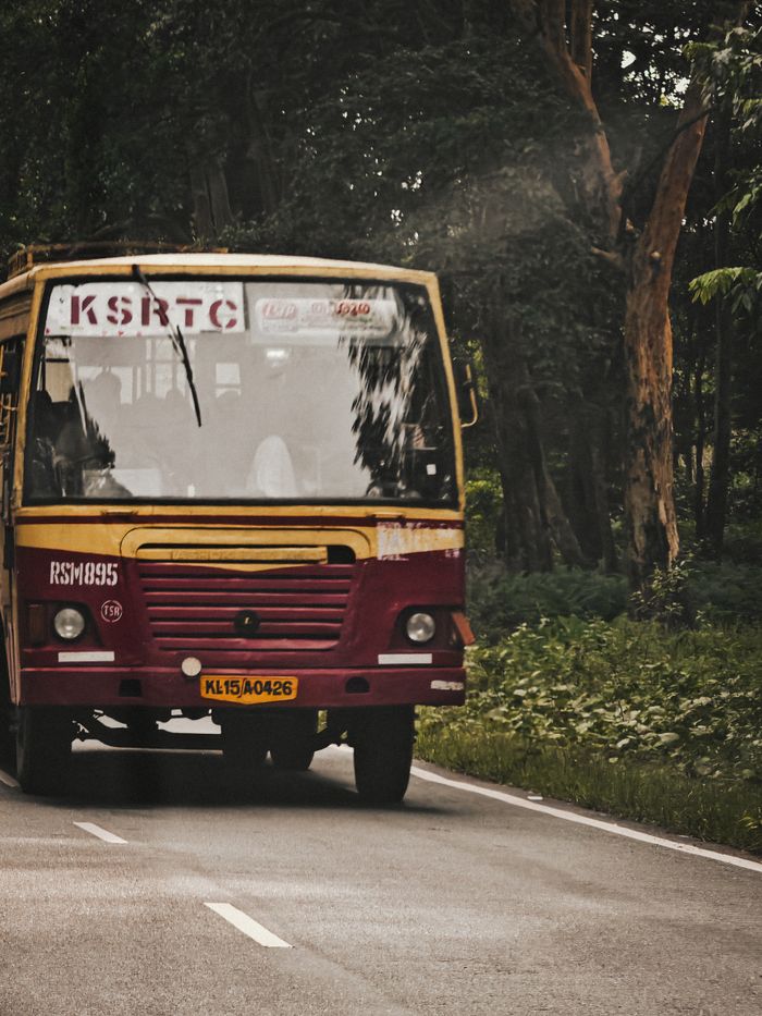 Crafting Captivating Headlines: Your awesome post title goes here A KSRTC bus travels through a lush, wooded road in Kerala, India, showcasing regional transportation.