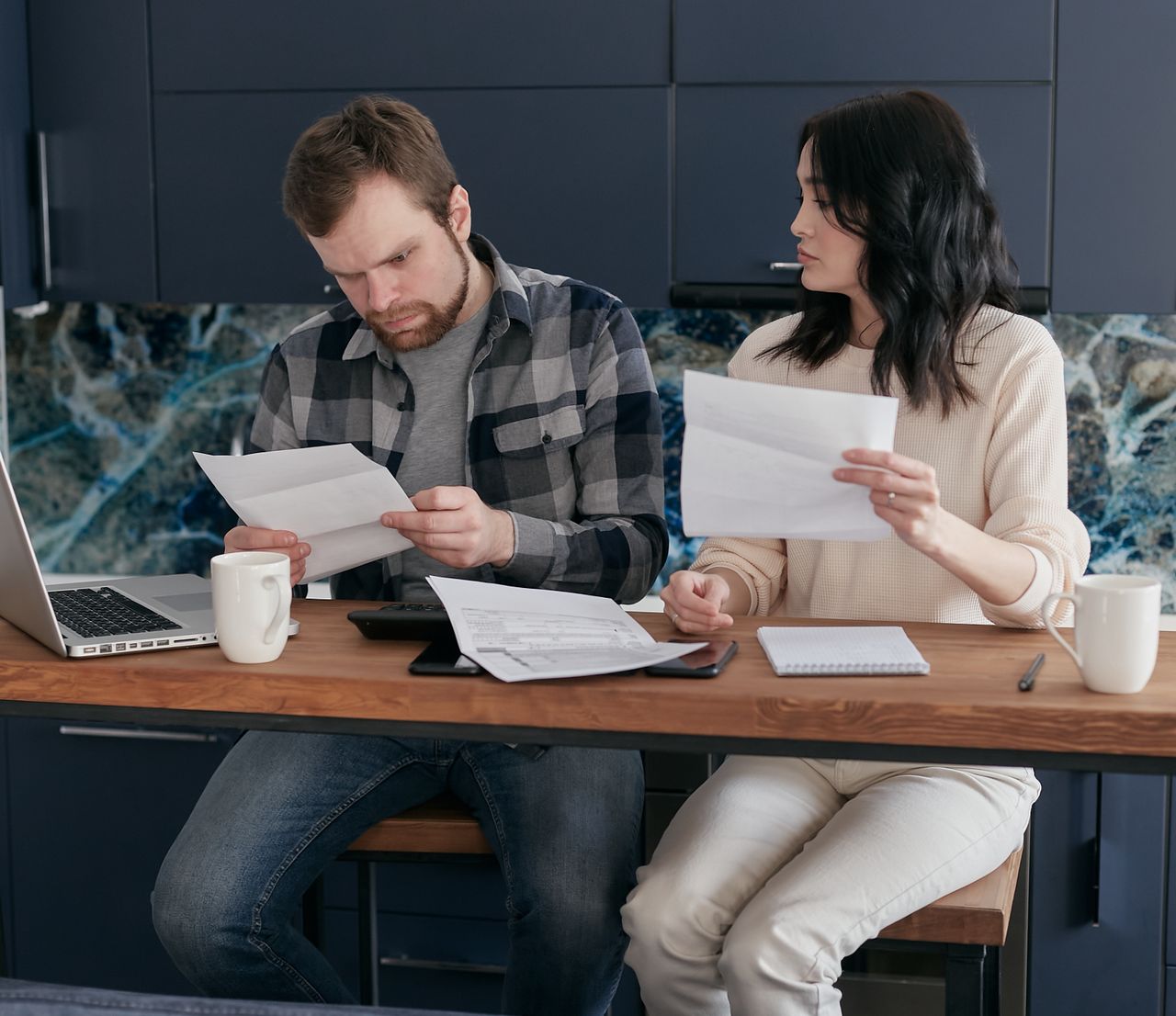 services-03 A young couple sits at home looking at financial documents with concern.