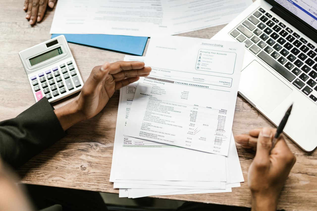 services-04 Hands holding financial documents with calculator and laptop on office desk, business analysis scene.